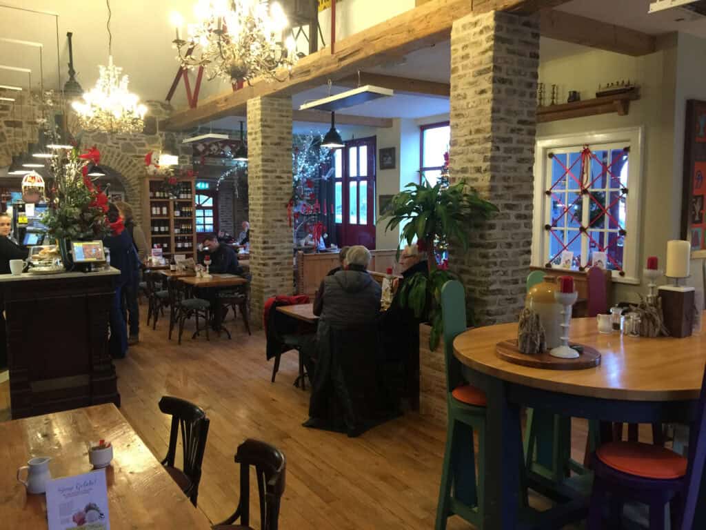 Warm and inviting café scene with holiday decorations, chandeliers, and wooden furnishings.